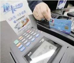  ?? — AFP ?? A cashier swipes a credit card at a Shanghai home-appliance store.