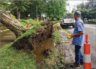  ?? KATE BARTLEY / STAFF ?? Utility crews used caution tape to rope off a section of sidewalk in Eaton where a tree was uprooted during storms Tuesday afternoon that brought high winds and heavy rain to the region.