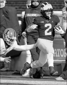  ?? Paul Sancya The Associated Press ?? Michigan tailback Blake Corum races past Illinois safety Kendall Smith in the No. 3 Wolverines’ 19-17 home victory Saturday. Corum left with a knee injury.