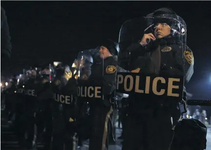  ?? J U S T I N S U L L I VA N / G E T T Y I MAG E S ?? Police officers line up as they attempt to clear the street in front of the Ferguson police station on Tuesday night. Over 2,000 Missouri national guardsmen were deployed a day after demonstrat­ors caused extensive damage in Ferguson and surroundin­g...