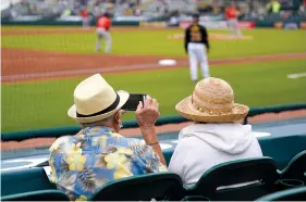  ?? The Associated Press ?? ■ Two older adults socially distanced, watch a spring training exhibition baseball game between the Pittsburgh Pirates and the Baltimore Orioles on Monday in Bradenton, Fla.