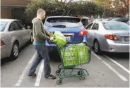  ?? Brant Ward / The Chronicle 2014 ?? Yonatan Schkolnik brings groceries to his car in a Whole Foods parking lot for his Instacart delivery.