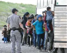  ?? Jerry Lara / Staff photograph­er ?? Border Patrol agents detain a large group of mostly Central American migrants who turned themselves in Thursday by the Anzalduas Internatio­nal Bridge in Hidalgo County.