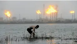  ?? —REUTERS ?? MONEYMAKER A man stands in Shatt al-Arab River with flames rising from an oil refinery in the background in Basra, Iraq, on July 23, 2020.