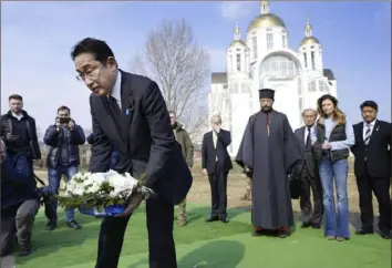  ?? Iori Sagisawa/Kyodo News via AP ?? Japanese Prime Minister Fumio Kishida, front, lays flowers Tuesday at a church in Bucha, a town outside Kyiv that became a symbol of Russian atrocities against civilians, in Ukraine.
