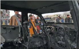  ?? (AP/Rahmat Gul) ?? People look at a damaged car Sunday after a bombing attack in Kabul, Afghanista­n. Afghanista­n’s Interior Ministry said that the blast killed at least eight people and wounded more than 15 others, including a member of parliament, Khan Mohammad Wardak.