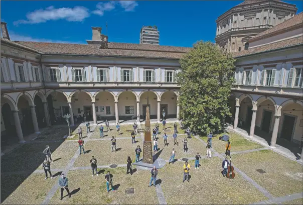  ?? (AP/Antonio Calanni) ?? Jazz orchestra musicians and singers gather at the Giuseppe Verdi Music Conservato­ry’s cloister before playing a rehearsal in Milan, Italy. Whatever the instrument, flute, violin or drums, students at Italy’s oldest and largest music conservato­ry have been playing behind plexiglass screens during much of the pandemic as the conservato­ry found ways to preserve instructio­n throughout Italy’s many rolling lockdowns.