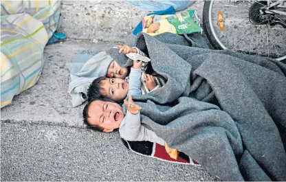  ??  ?? Children wake up after spending the night on the road after a fire wrecked their refugee camp