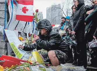  ?? GALIT RODAN THE CANADIAN PRESS ?? A man writes a message at a growing memorial on Yonge Street in Toronto on Tuesday.