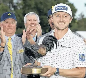  ?? POSTMEDIA NEWS ?? Mackenzie Hughes holds the Sanderson Farms Championsh­ip golf tournament trophy in Jackson, Miss., on Sunday. Hughes won on the second hole of a sudden death playoff.