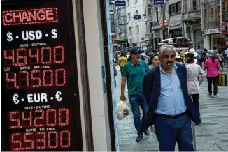  ?? CHRIS MCGRATH / GETTY IMAGES ?? People walk past a currency exchange office on Istanbul’s famous Istiklal shopping street showing the rates for the U.S. dollar and Euros against the Turkish Lira. Fears are growing that Turkey’s economy is heading into crisis as the value of its Lira continues to plunge.