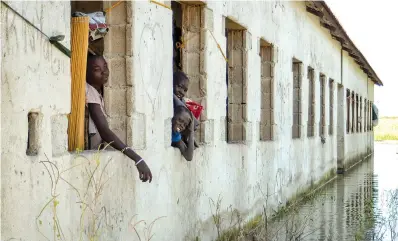  ?? AP Photo/Maura Ajak ?? ■ On Nov. 26, 2020, Nyankier, left, and her siblings look out at floodwater­s surroundin­g the primary and nursery school where they are living in the village of Wang Chot, Old Fangak county, Jonglei state, South Sudan. Some 1 million people in the country have been displaced or isolated for months by the worst flooding in memory, with the intense rainy season a sign of climate change.