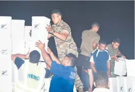  ?? Picture (above) / NZDF ?? Tongan soldiers unload aid from an RNZAF Hercules while a family (right) dry their possession­s after the storm ripped their roof off.