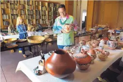  ?? GREG SORBER/JOURNAL ?? Jeanie Higgins, left, assistant to the director of the Wheelwrigh­t Museum of the American Indian, and Ken Williams, Case Trading Post manager, prepare donated artwork for the museum’s annual auction.