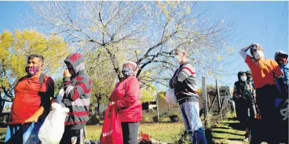  ?? AP ?? People line up to receive food handouts from soldiers during a government-ordered lockdown to curb the spread of the new coronaviru­s in Buenos Aires, Argentina, on Wednesday, April 29. The province is in the process of restructur­ing its debt.