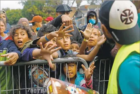  ?? Gary Coronado Los Angeles Times ?? CUSTOMS officials have stopped freelance photojourn­alists, advocates and volunteers for interrogat­ions regarding their interactio­ns with migrants in Tijuana. Above, children reach out for boxes of cereal during a food distributi­on in front of the Benito Juarez Sports Center.