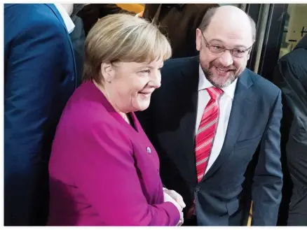  ??  ?? German Chancellor Angela Merkel, left, and the leader of Germany’s Social Democratic party, Martin Schulz, shake hands in Berlin Sunday. (AP)