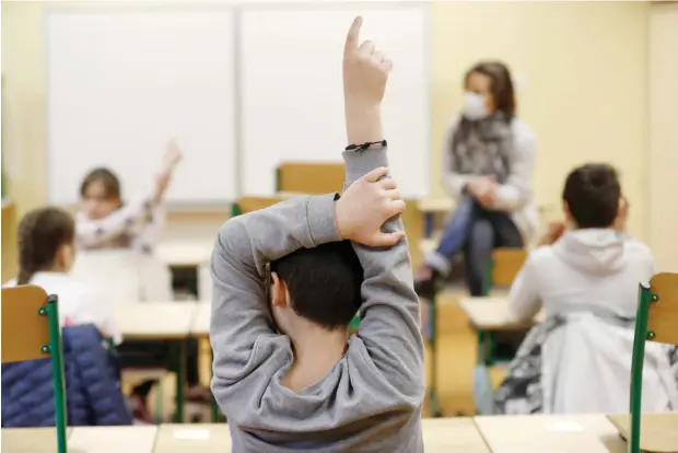  ??  ?? In this May 14, 2020 file photo, schoolchil­dren raise their fingers to answer their teacher Sandrine Albiez, wearing a face mask, in a school in Strasbourg, eastern France. Just days after around a third of French schoolchil­dren went back to school, ending the gruelling coronaviru­s-linked lockdown, there has been flare up of about 70 cases with coronaviru­s in classes. (AP)