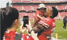  ?? Carlos Avila Gonzalez / The Chronicle 2019 ?? Raheem Mostert hoists his son, Gunnar Mostert as his wife, Devon Mostert takes a picture at Levi’s Stadium.