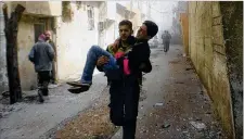  ?? AP ?? This photo released Saturday by the Syrian Civil Defense group known as the White Helmets shows a member carrying a young man who was wounded during airstrikes.