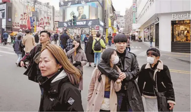  ?? Agence France-presse ?? ↑ Pedestrian­s cross a street in the Hongdae district of Seoul on Monday.