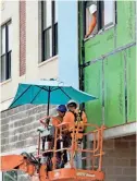  ?? MAX BECHERER/THE ADVOCATE VIA AP ?? Constructi­on workers keep out of the sun with an umbrella on their boom lift as they work on an apartment building along South Jefferson Davis Parkway in New Orleans on Aug. 13.