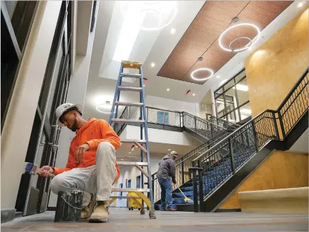  ?? MATT DAHLSEID/THE NEW MEXICAN ?? Workers paint and mop Friday near the entrance of the new Santa Fe County administra­tive complex.