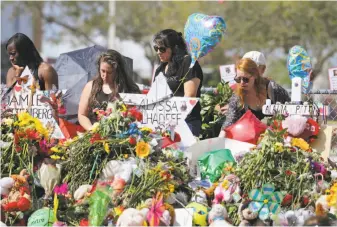  ?? David Santiago / Miami Herald ?? Mourners pay tribute at a memorial for the 17 victims of the shooting at Marjory Stoneman Douglas High School in Parkland, Fla. Students will return to classes Wednesday.