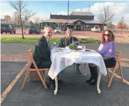  ?? COURTESY OF VINCE CLAPPER ?? Vince Clapper and his parents set up a dinner table in the Texas Roadhouse parking lot in Sioux Falls, S.D., to celebrate his graduation from Grand Canyon University.