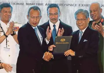  ?? PIC BY DANIAL SAAD ?? Defence Ministry secretary-general Datuk Seri Abdul Rahim Mohd Radzi (second from left) exchanging documents with Boustead Naval Shipyard Sdn Bhd chief executive Tan Sri Lodin Che Wok in Langkawi yesterday.
With them is Defence Minister Datuk Seri...