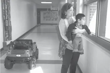  ?? Angela Piazza/The Victoria Advocate via AP ?? ■ Occupation­al therapist Amanda Kern holds Abel Salazar, 4, up so he can look out the window on Jan. 31 at Dudley Elementary in Victoria, Texas. Abel is part of the preschool program for children with disabiliti­es. Victoria West High School math and...