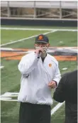  ??  ?? Head coach Art Abreu Jr. speaks to his players over a microphone during a water break on the first day of summer workouts on Monday (June 15) at Anaya Stadium in Taos.