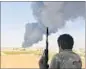  ?? REUTERS ?? A fighter watches as smoke rises after rockets hit a fuel tank in Tripoli on Sunday.