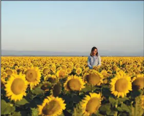  ?? MIKE KAI CHEN / THE NEW YORK TIMES ?? Kim Gallagher, a rice farmer, stands in a field of her sunf lowers, which require far less water than rice, in the Sacramento Valley of California. Drought is transformi­ng the state, with broad consequenc­es for the food supply.