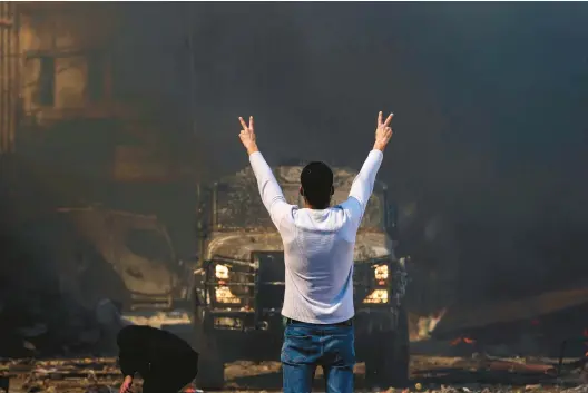  ?? ZAIN JAAFAR/GETTY-AFP ?? A Palestinia­n man flashes the victory sign at an Israeli military vehicle Wednesday in the West Bank.