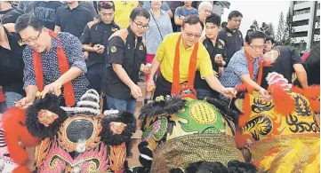  ??  ?? Lo (centre) dotting the eyes of a lion, accompanie­d by Tan (right) and Sih.