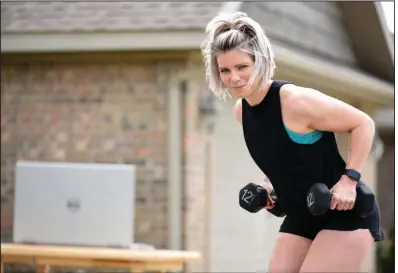  ?? (NWA Democrat-Gazette/David Gottschalk) ?? Betsy Rawlings, a personal trainer with Fayettevil­le Athletic Club, demonstrat­es an online workout in the driveway of her home in Springdale. With fitness gyms closed because of coronaviru­s, trainers are having to be creative in order to train their clients, using social media platforms like Zoom, Instagram and Facebook Live. Visit nwaonline.com/200415Dail­y/ and nwadg.com/photos for a photo gallery.