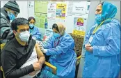  ?? —AFP ?? A health worker inoculates a staff member with Covid-19 vaccine at the GB Pant hospital in Srinagar on Friday.