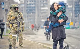  ?? AFP ?? A woman holds and kisses a child next to Russian soldiers in a street of Mariupol, Ukraine on Tuesday.