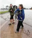  ?? Karen Warren / Houston Chronicle ?? Evacuee Shelly Jones gets help carrying her dogs out of a boat that carried them to safety.