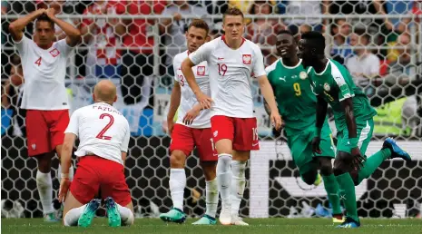  ?? Picture: YURI KOCHETKOV, EPA ?? THE SMILES AND FROWNS OF RUSSIA: Thiago Cionek of Poland reacts after deflecting the ball into his own goal as Senegal players celebrate yesterday.