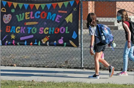  ?? RICK BOWMER — ASSOCIATED PRESS ?? Cimmie Hunter, left, and Cadence Ludlow, both 6th graders, arrive at Liberty Elementary School during the first day of class in Murray, Utah. For countless families across the country, the school year is opening in disarray and confusion.