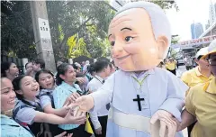  ?? PATIPAT JANTHONG ?? Catholic school students shake hands with a mascot of Pope Francis as they wait for the pope to arrive at the Holy See’s embassy on Sathon Road.