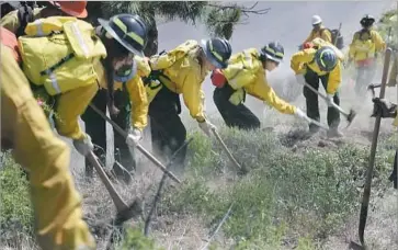  ??  ?? THE TRAINEES attack the imaginary blaze, cutting a fire line around the perimeter. When they’re finally done, they charge back up the slope, hoisting backpacks brimming with hose, to knock down the embers.