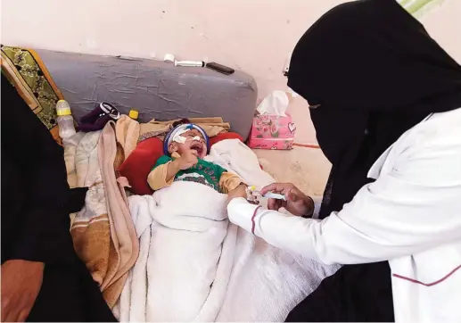  ?? —AFP ?? SANAA: A Yemeni doctor makes an injection to a baby at a Kuwaiti hospital in the Yemeni capital Sanaa. One and a half million children suffer from malnutriti­on, including 370,000 for whom it is so severe it weakens their immune system, the UN...
