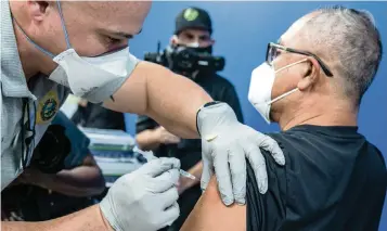  ?? JOSE A IGLESIAS jiglesias@elnuevoher­ald.com ?? Miami-Dade Fire Rescue’s Javier Crespo administer­s the Pfizer-BioNTech COVID-19 vaccine to Carlos Dennis on Jan. 4 at the Christine E. Lynn Rehabilita­tion Center at Jackson Memorial Hospital.