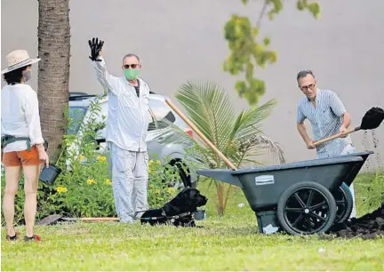  ?? AMY BETH BENNETT/SOUTH FLORIDA SUN SENTINEL PHOTOS ?? Scott Strawbridg­e, center, waves at the next tree planter, Karen Gavrilov, as Fort Lauderdale architect and urban farmer Michael Madfis shovels.