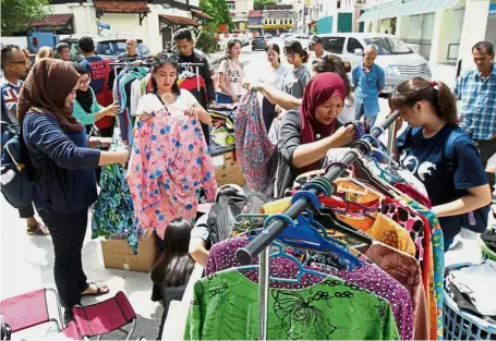  ??  ?? Getting ready: Dr Rusaslina (wearing maroon tudung) and her group of volunteers hanging clothes to be given away.