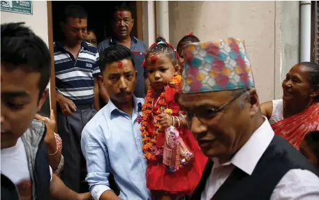  ??  ?? Newly appointed Living Goddess Kumari of Kathmandu Trishna Shakya (3) is carried by her father towards the Kumari palace