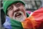  ?? MARK LENNIHAN-THE ASSOCIATED PRESS ?? In this Monday, March 17, 2014 photo, artist Gilbert Baker, designer of the Rainbow Flag, is draped with the flag while protesting at the St. Patrick’s Day parade in New York.